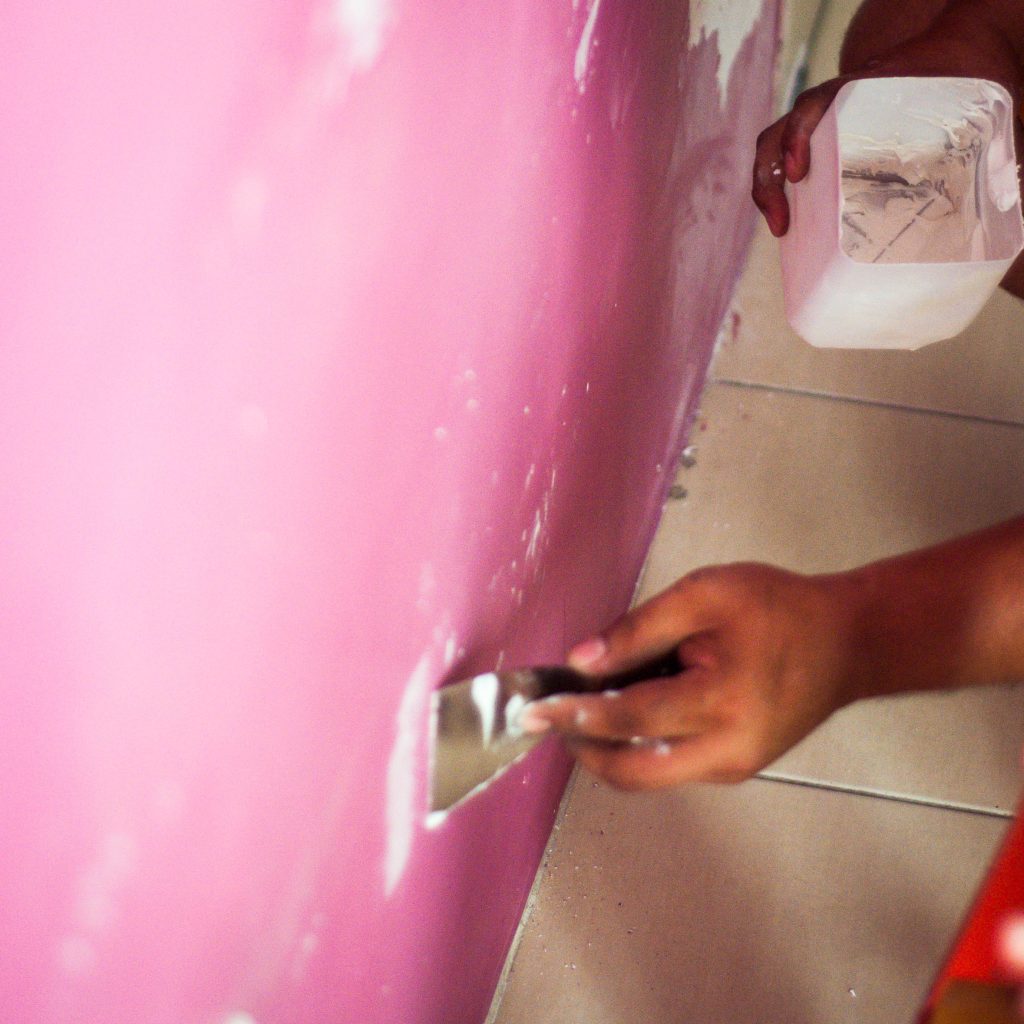 close-up-hand-holding-scrapper-colored-wall